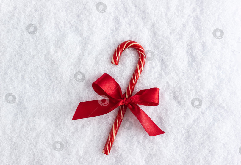 Скачать Новогодняя конфета украшенная красным бантом лежит на снегу фотосток Ozero