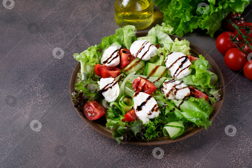 Скачать Салат с сыром моцарелла, листьями салата, огурцами и помидорами со специями и оливковым маслом, политый бальзамической глазурью фотосток Ozero