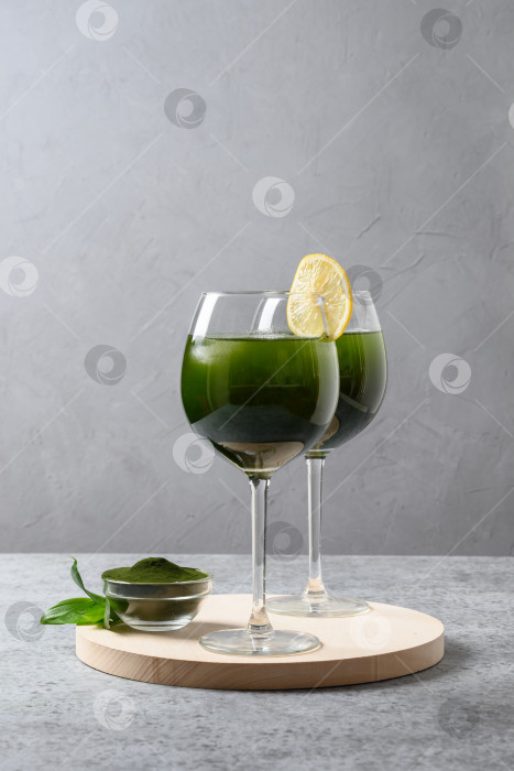 Скачать Два напитка из хлореллы с лимоном в стакане на сером фоне. фотосток Ozero