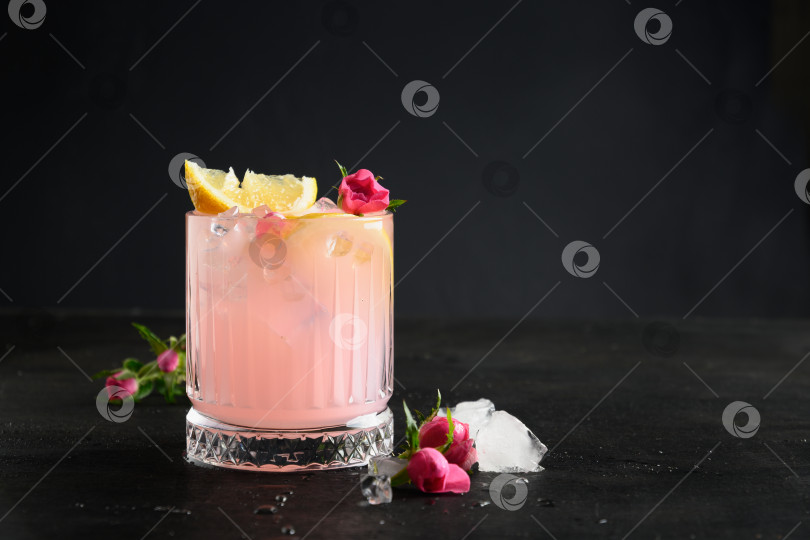 Скачать Разливка розового алкогольного коктейля с розовыми цветами на черном фоне. фотосток Ozero