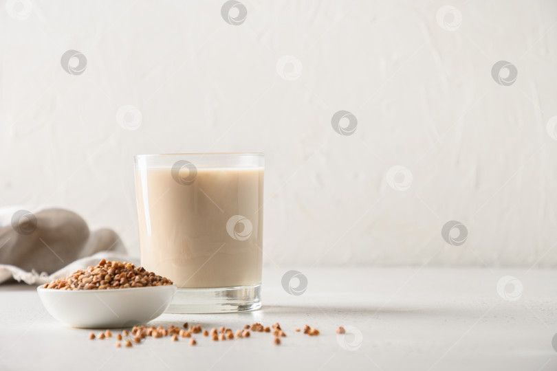 Скачать Полезное гречневое молоко в стакане с зерновым ингредиентом на белом фоне. Горизонтальная ориентация. Пространство для копирования. фотосток Ozero