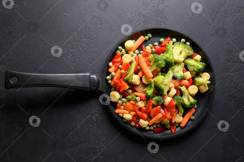 Скачать Замороженные овощи на сковороде на черном фоне. Вид сверху. фотосток Ozero