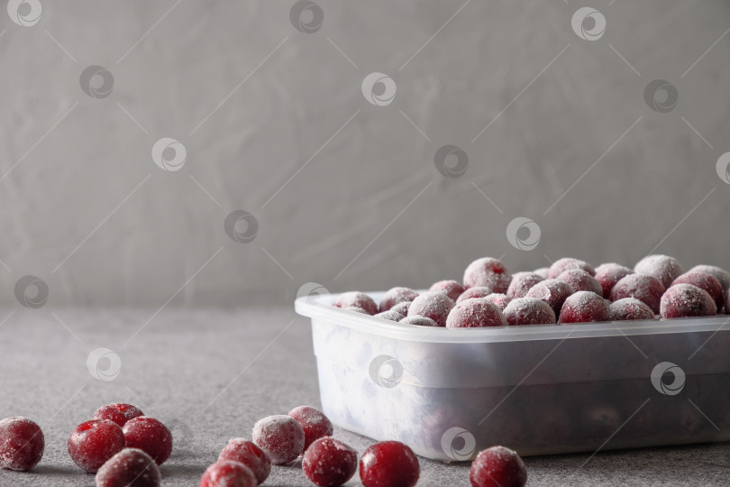 Скачать Замороженная красная вишня в контейнере на сером фоне. фотосток Ozero