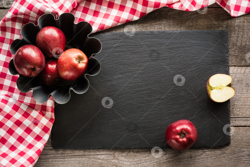 Скачать Спелые красные яблоки на деревянной доске, обернутой красным клетчатым полотенцем. Скопируйте место для текста на тарелке из black slate. фотосток Ozero