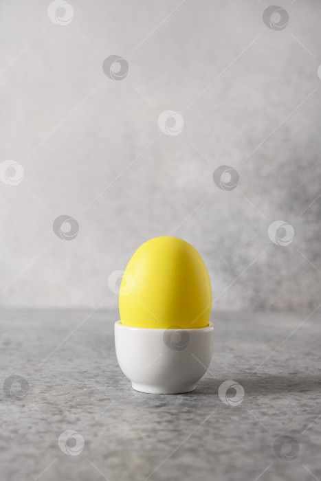 Скачать Пасхальное желтое яйцо в подставке для праздничного завтрака в минималистичном стиле. фотосток Ozero
