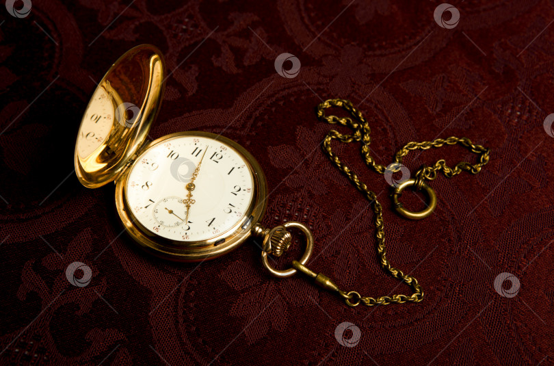 Скачать Золотые карманные часы на темно-бордовой ткани фотосток Ozero