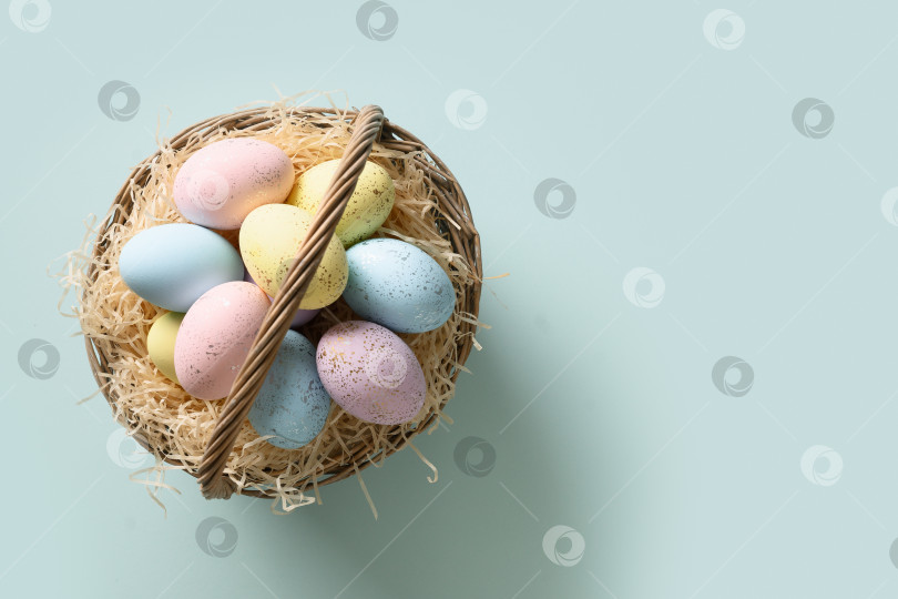 Скачать Пасхальные пастельные яйца в плетеной корзине для счастливого праздника на синем фоне. фотосток Ozero