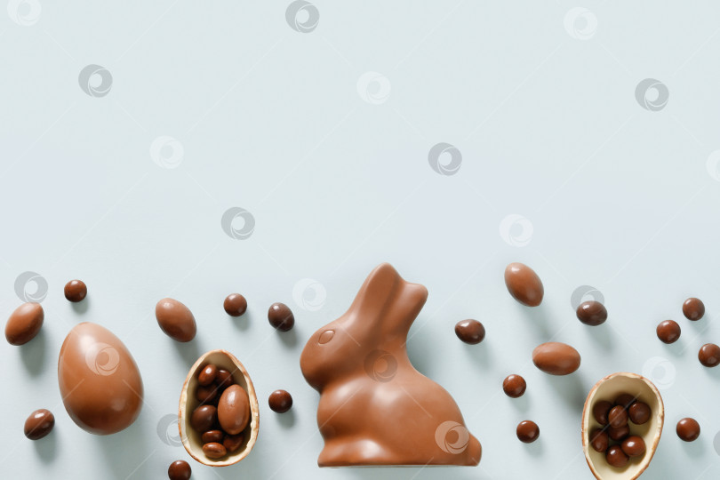 Скачать Поздравительная открытка с Пасхой с шоколадными конфетами, кроликом, яйцами. Концептуальная охота за яйцами. фотосток Ozero