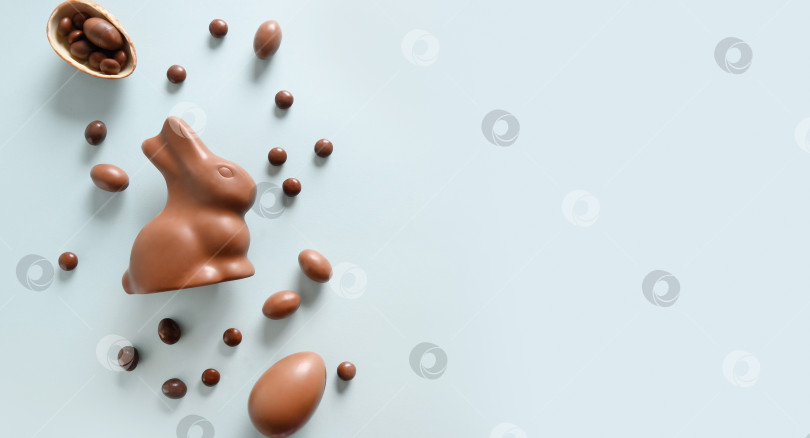 Скачать Поздравительная открытка с Пасхой с шоколадными конфетами, кроликом, яйцами. Концептуальная охота за яйцами. фотосток Ozero