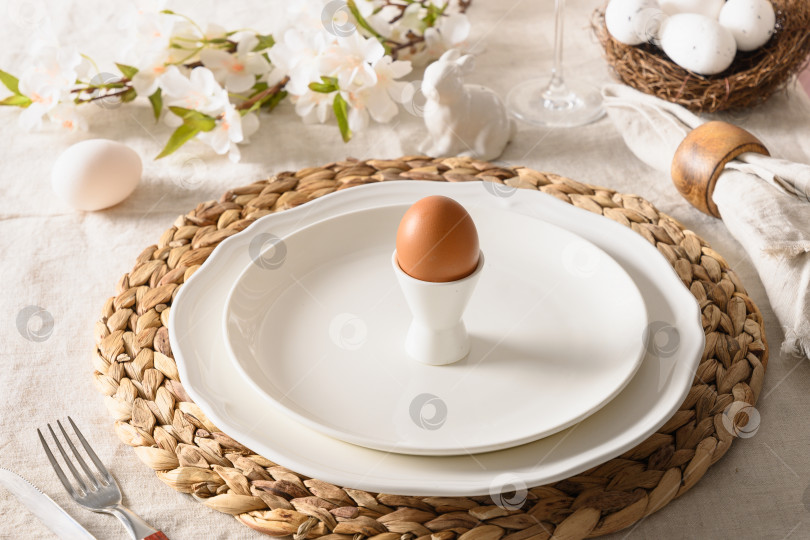 Скачать Праздничная сервировка весеннего пасхального стола с органическим коричневым яйцом и белым кроликом. фотосток Ozero
