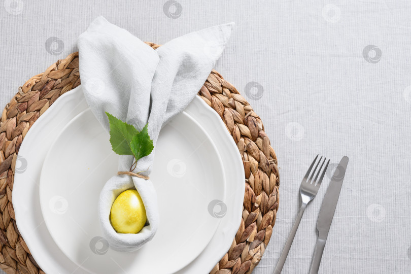 Скачать Пасхальная сервировка стола с желтым цыпленком, яйцами, свежими цветами на серой льняной скатерти. фотосток Ozero