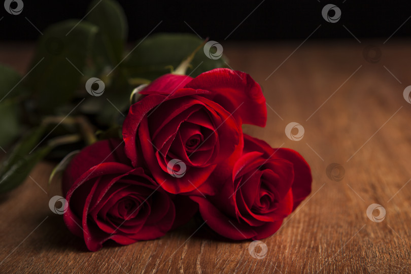 Скачать букет роз, лежащий на деревянном столе на черном фоне фотосток Ozero