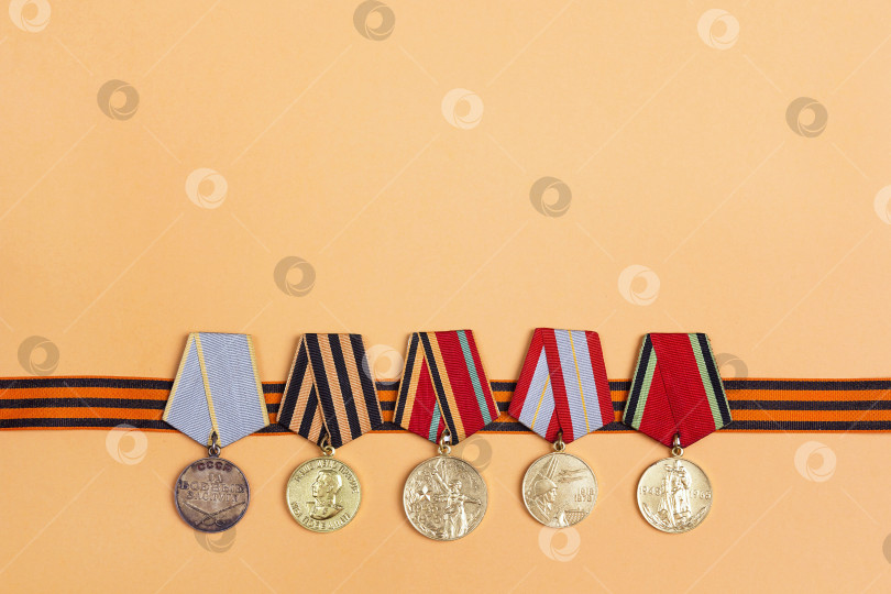 Скачать Предыстория 9 мая. Георгиевская лента и медали Великой Отечественной войны на оранжевом фоне фотосток Ozero