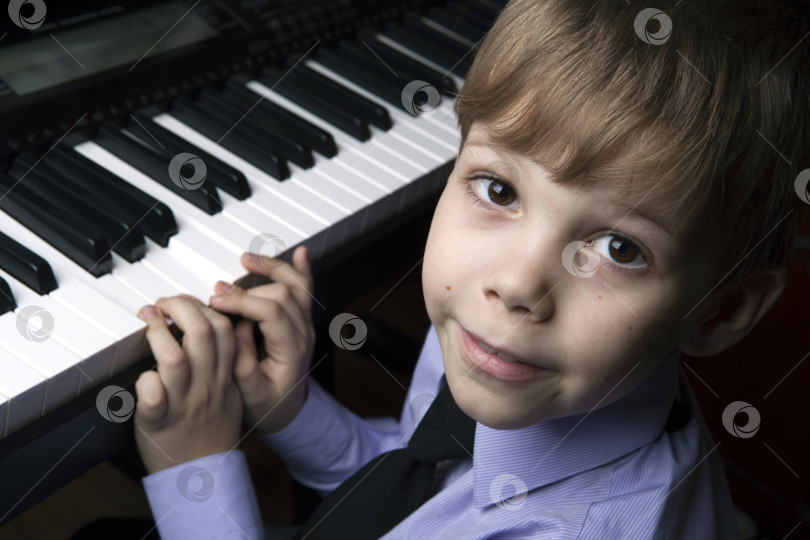 Скачать улыбающийся маленький мальчик, сидящий за пианино фотосток Ozero