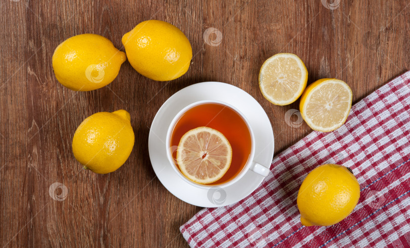 Скачать Натюрморт из свежих лимонов на деревянном столе с чашкой чая фотосток Ozero