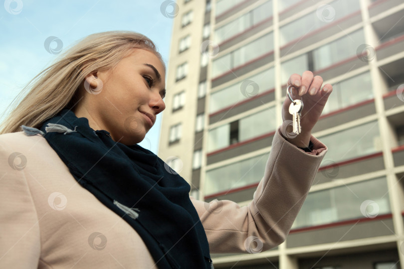 Скачать красивая девушка держит в руках ключи от квартиры на фоне новостроек фотосток Ozero