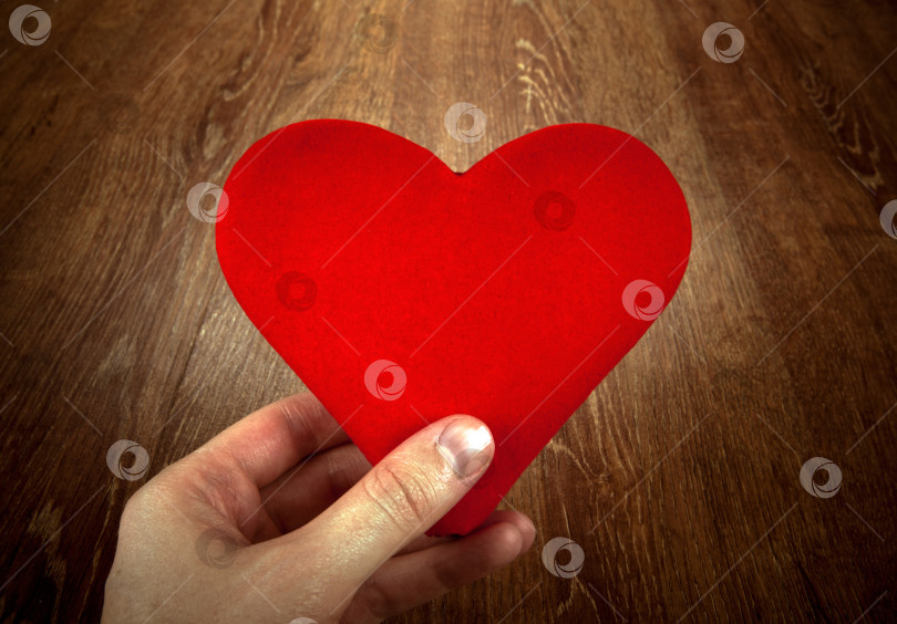 Скачать символ красного сердца на деревянном фоне в руке человека фотосток Ozero