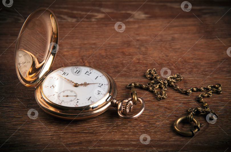 Скачать На деревянном столе лежат старинные золотые карманные часы фотосток Ozero