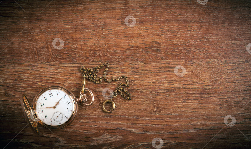 Скачать На деревянном столе лежат старинные золотые карманные часы фотосток Ozero
