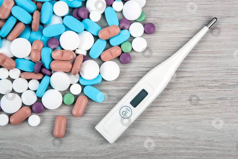 Скачать фон из множества разноцветных медицинских таблеток и термометра, вид сверху фотосток Ozero