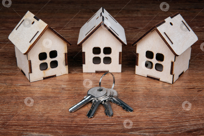 Скачать три деревянных миниатюрных домика и ключ от двери на деревянном фоне фотосток Ozero