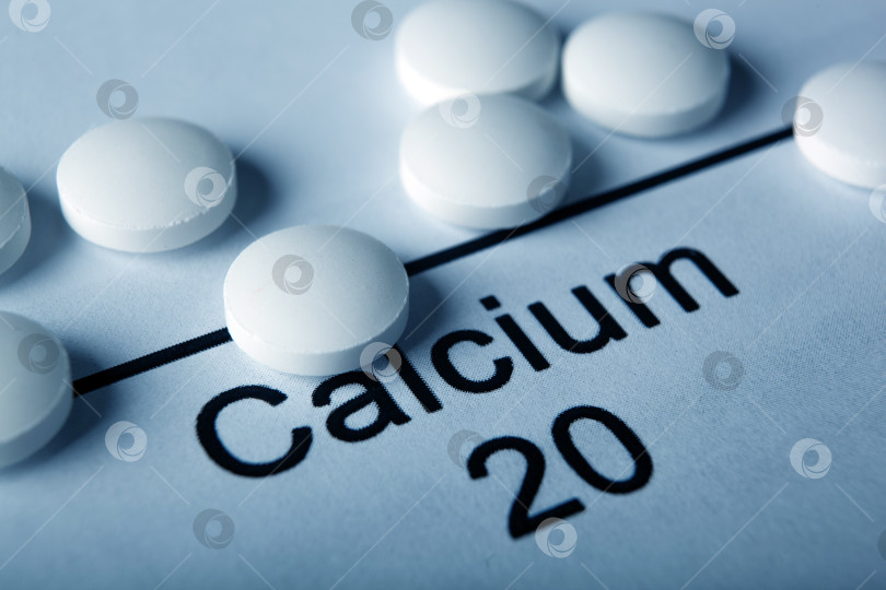 Скачать белые таблетки с кальцием и надписью химического элемента Calcium фотосток Ozero