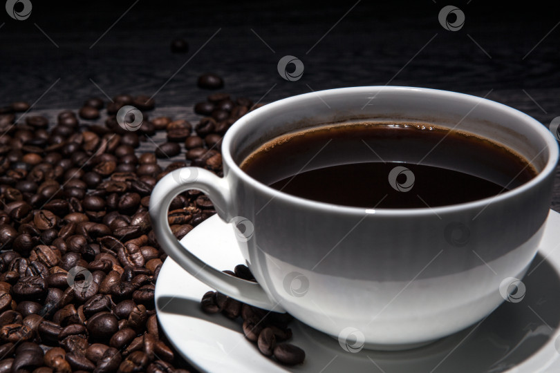 Скачать чашка горячего кофе и обжаренных кофейных зерен на деревянном столе фотосток Ozero
