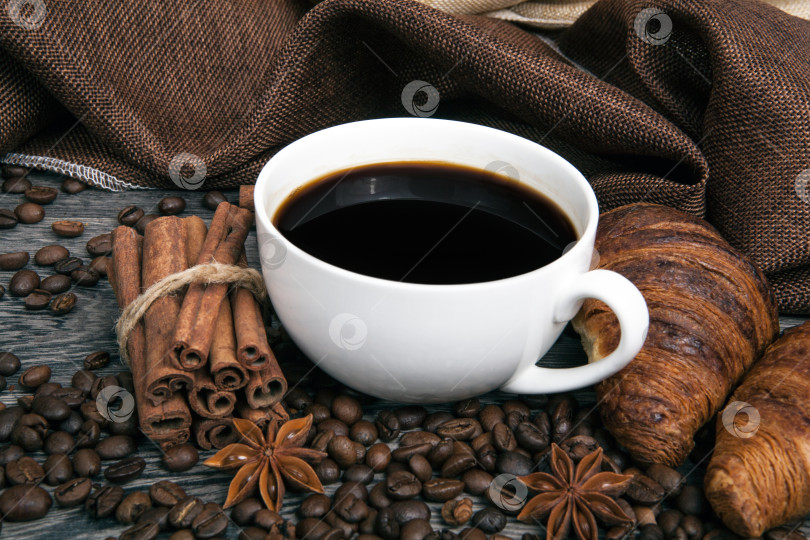 Скачать чашка горячего кофе в обжаренных кофейных зернах с поджаренными круассанами фотосток Ozero