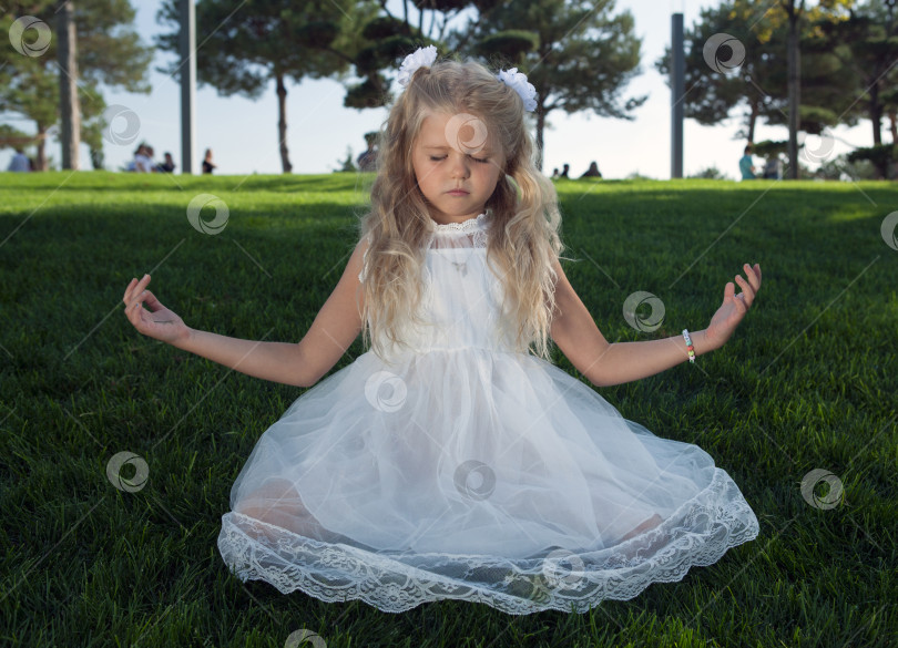 Скачать маленькая девочка в белом платье на зеленой лужайке фотосток Ozero