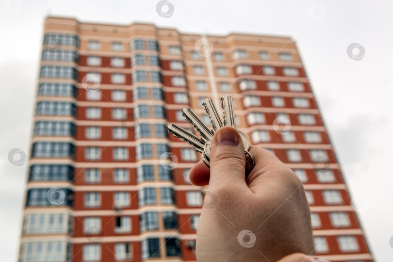 Скачать связка ключей от квартиры в руке мужчины на фоне нового здания фотосток Ozero