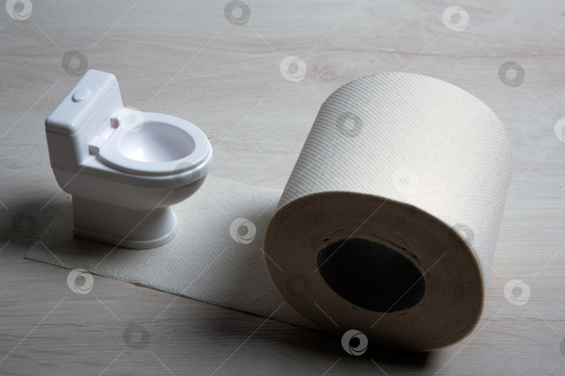 Скачать миниатюрный унитаз с рулоном туалетной бумаги на столе фотосток Ozero