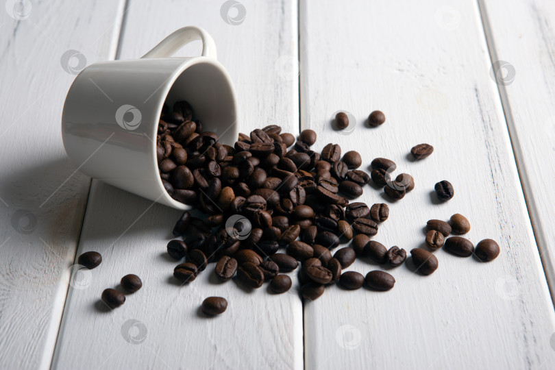 Скачать обжаренные кофейные зерна в чашке на белом деревянном фоне фотосток Ozero