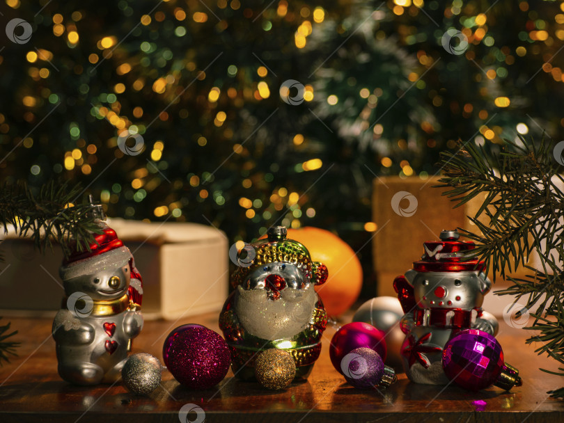 Скачать Рождественская елка с разноцветными рождественскими шарами и подарочными коробками на сверкающем фоне. Праздничное рождественское украшение. Праздничное оформление с рождественской елкой, подарками и украшениями на деревянном столе фотосток Ozero