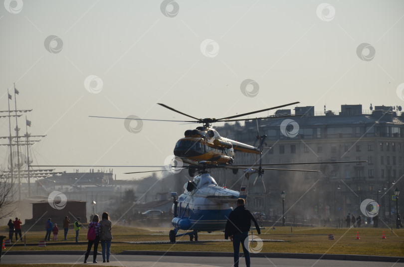 Скачать Санкт-Петербург, Россия - 04.15.2018: Люди наблюдают за посадкой прогулочного вертолета на площадку рядом с Петропавловской крепостью в Санкт-Петербурге фотосток Ozero