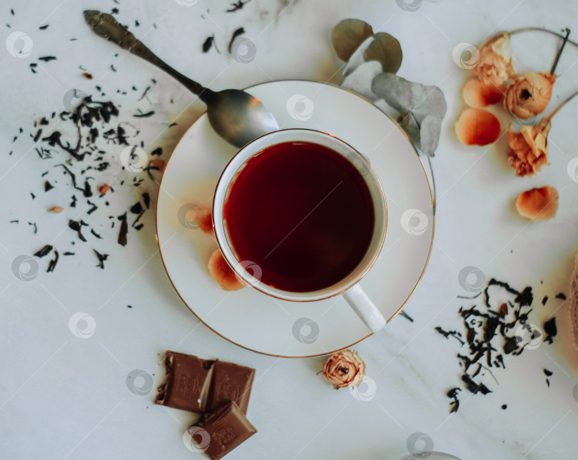 Скачать Белая чашечка с ароматным чаем шоколадом и цветами на мраморном столе вид сверху фотосток Ozero