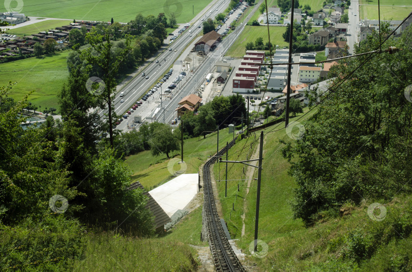 Скачать Неровные рельсы, ведущие к горе Пилатус в Люцерне, Швейцария. Вид с высоты птичьего полета на железнодорожный вокзал и автостоянку. фотосток Ozero