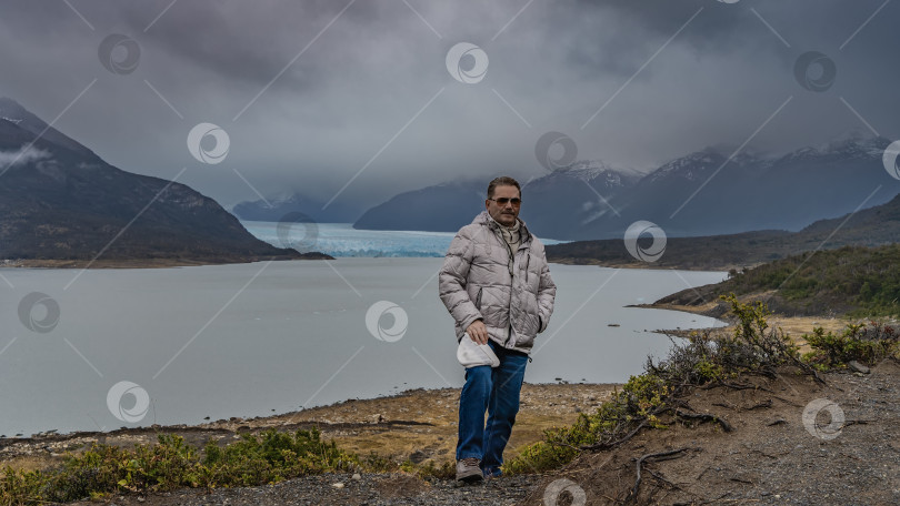 Скачать Мужчина в пуховике стоит на фоне ледникового озера. фотосток Ozero