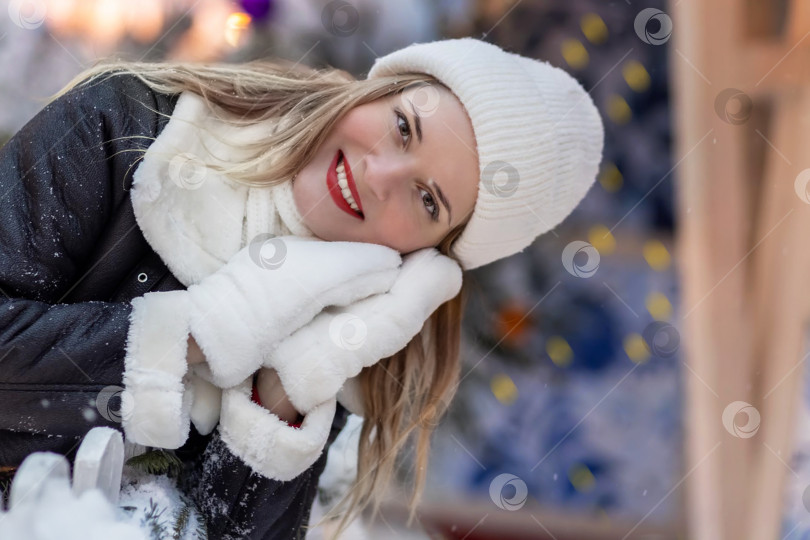 Скачать Молодая женщина в зимней теплой одежде и шапке стоит у заснеженной рождественской елки. Празднование Нового года, Рождества фотосток Ozero