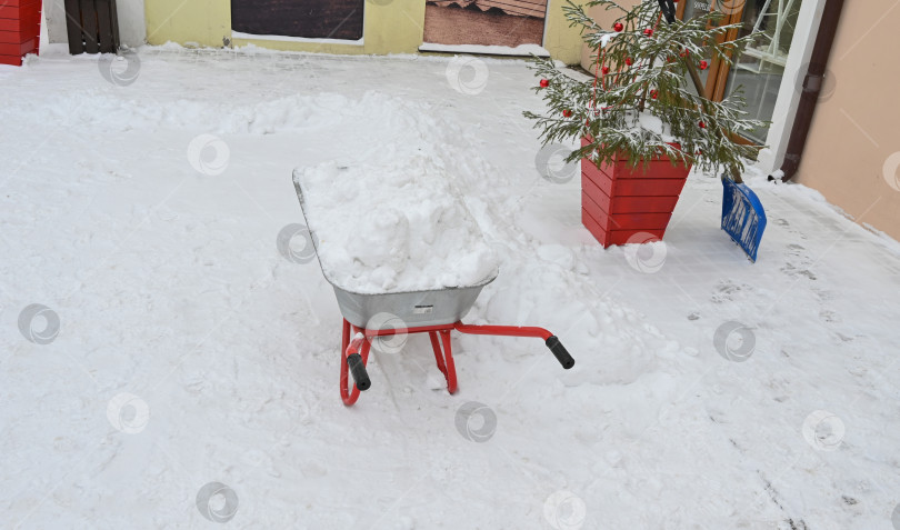 Скачать Металлическая тачка с грязным снегом, уборка улиц. Уборка снега в городе, строительные работы, озеленение города зимой фотосток Ozero