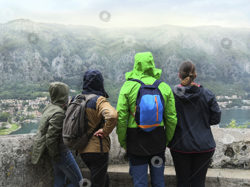 Скачать Компания из четырех молодых людей любуется прекрасным горным пейзажем. Котор, Черногория, вид сверху. фотосток Ozero