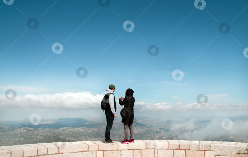 Скачать парень и девушка фотографируют красивый горный пейзаж с высоты каменной башни. фотосток Ozero
