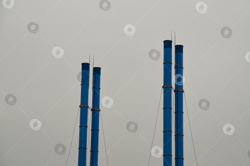 Скачать Голубые фабричные трубы на фоне серого неба. Индустриальный пейзаж. фотосток Ozero