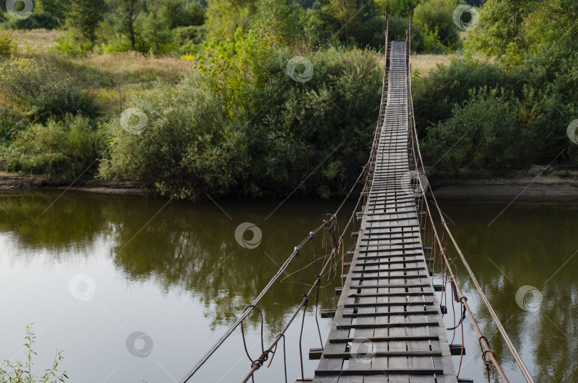 Скачать Старый деревянный подвесной мост через реку в дикой местности. фотосток Ozero