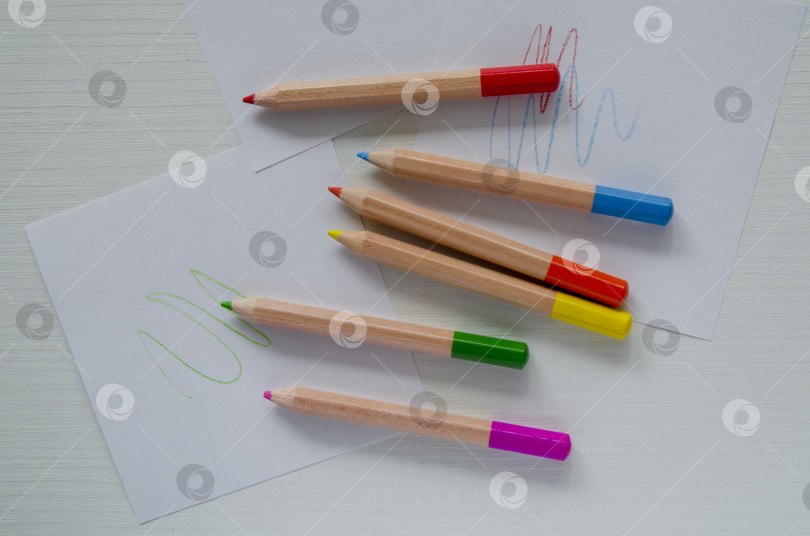 Скачать Маленькие цветные карандаши и листы белой бумаги на столе, вид сверху. Шаблон, место для рисования, письма, набросков. фотосток Ozero