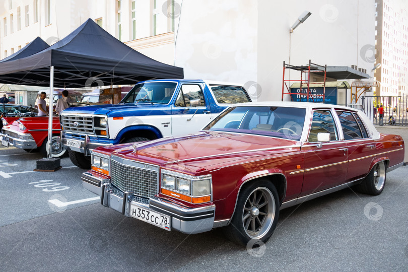 Скачать Красный Cadillac Fleetwood Brougham и белоголубой пикап Ford на выставках ретроспектива оригинальной встречи - Санктпетербург, Россия, Сентябрь 2023 фотосток Ozero