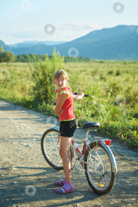 Скачать Девушка едет на велосипеде по сельской местности. Каникулы и летний день. фотосток Ozero
