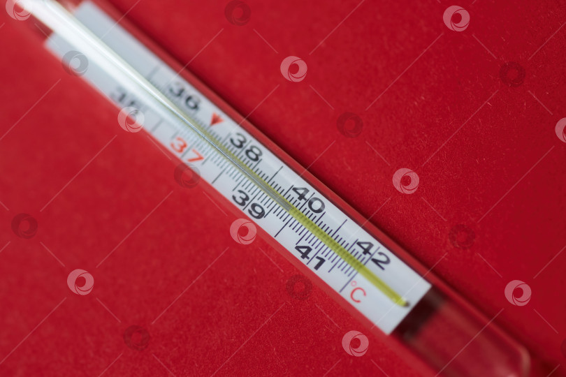 Скачать Классический ртутный термометр со шкалой градусов Цельсия и высокой температурой расположен на красном фоне. Понятие болезни, инфекции и коронавируса. фотосток Ozero