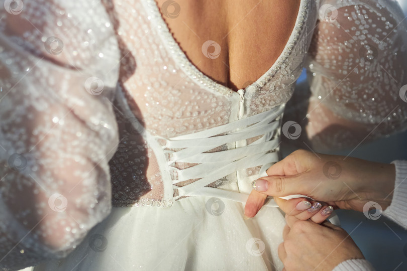 Скачать Шнуровка платья невесты. Корсет свадебного платья выполнен из шифона с вышивкой и блестками. фотосток Ozero