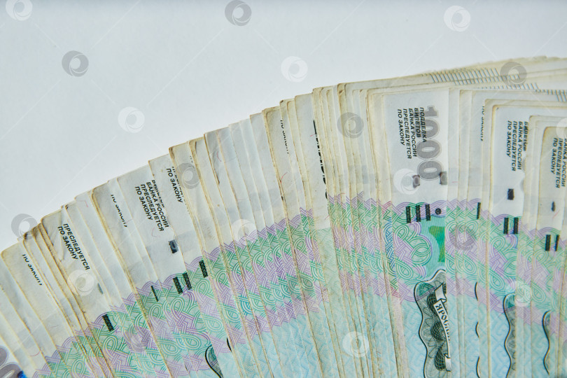 Скачать Российские банкноты номиналом 1000 рублей лежат на белой поверхности большой стопкой денег. Концепция экономики и банковской системы. фотосток Ozero