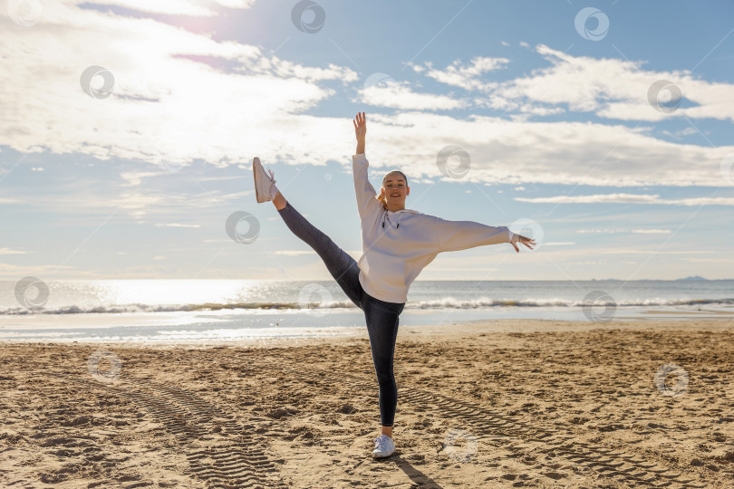 Скачать Красивая энергичная молодая женщина занимается гимнастикой на пляже фотосток Ozero